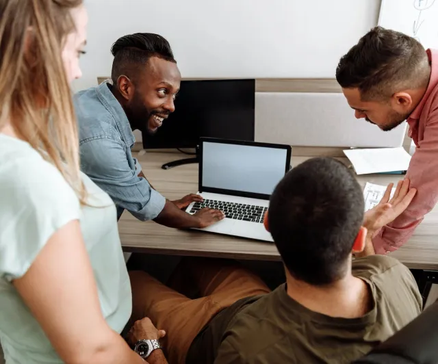 Four people working around a laptop